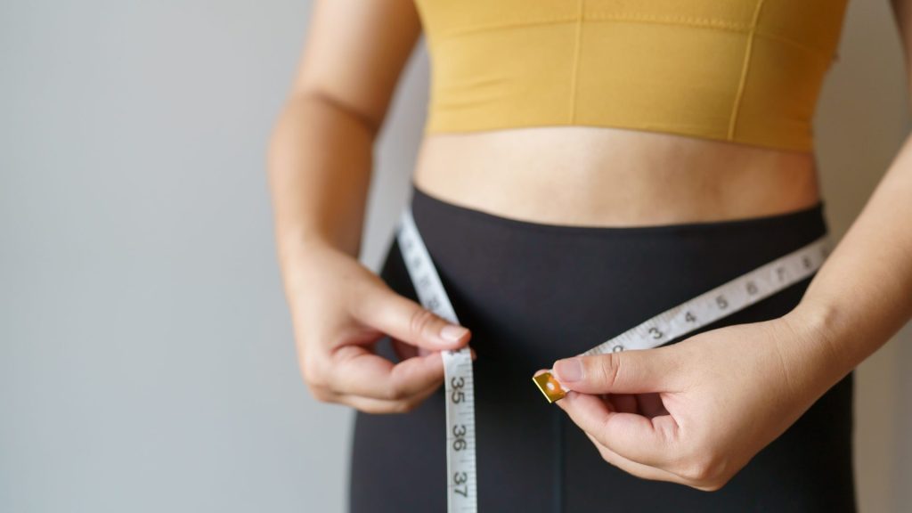 A woman measuring her waist