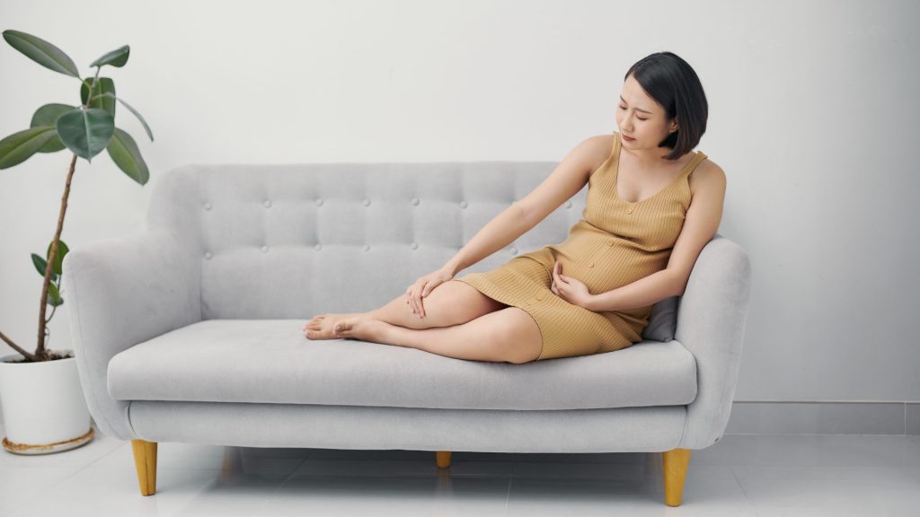 A woman sitting on a sofa, concerned about swelling
