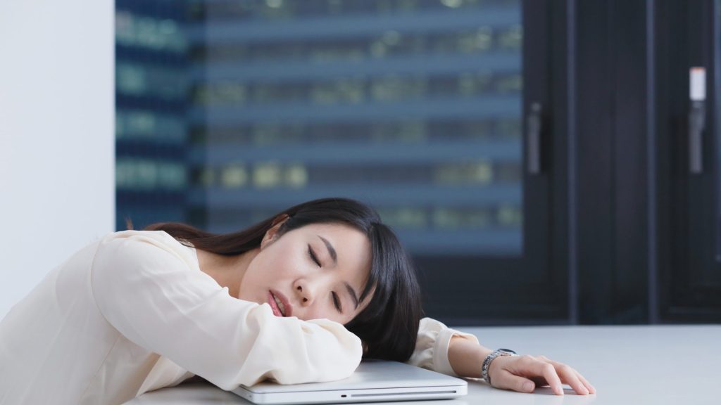 机の上で休んでいる女性